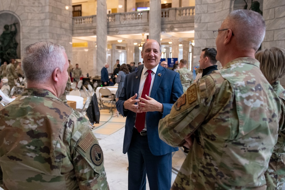 Gary Harter, center, speaks with uniformed service members in the Utah State Capitol rotunda.