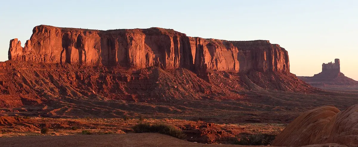 Sunlit red mesa and buttes at Monument Valley at sunrise