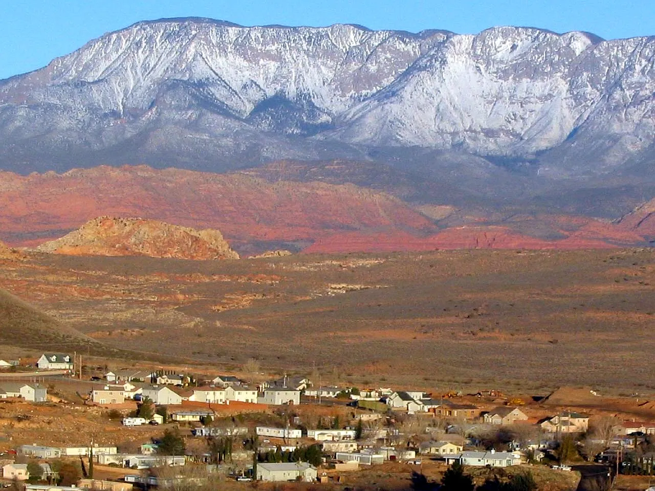 Hurricane's neighborhoods below red-rock hills and snow-capped mountains